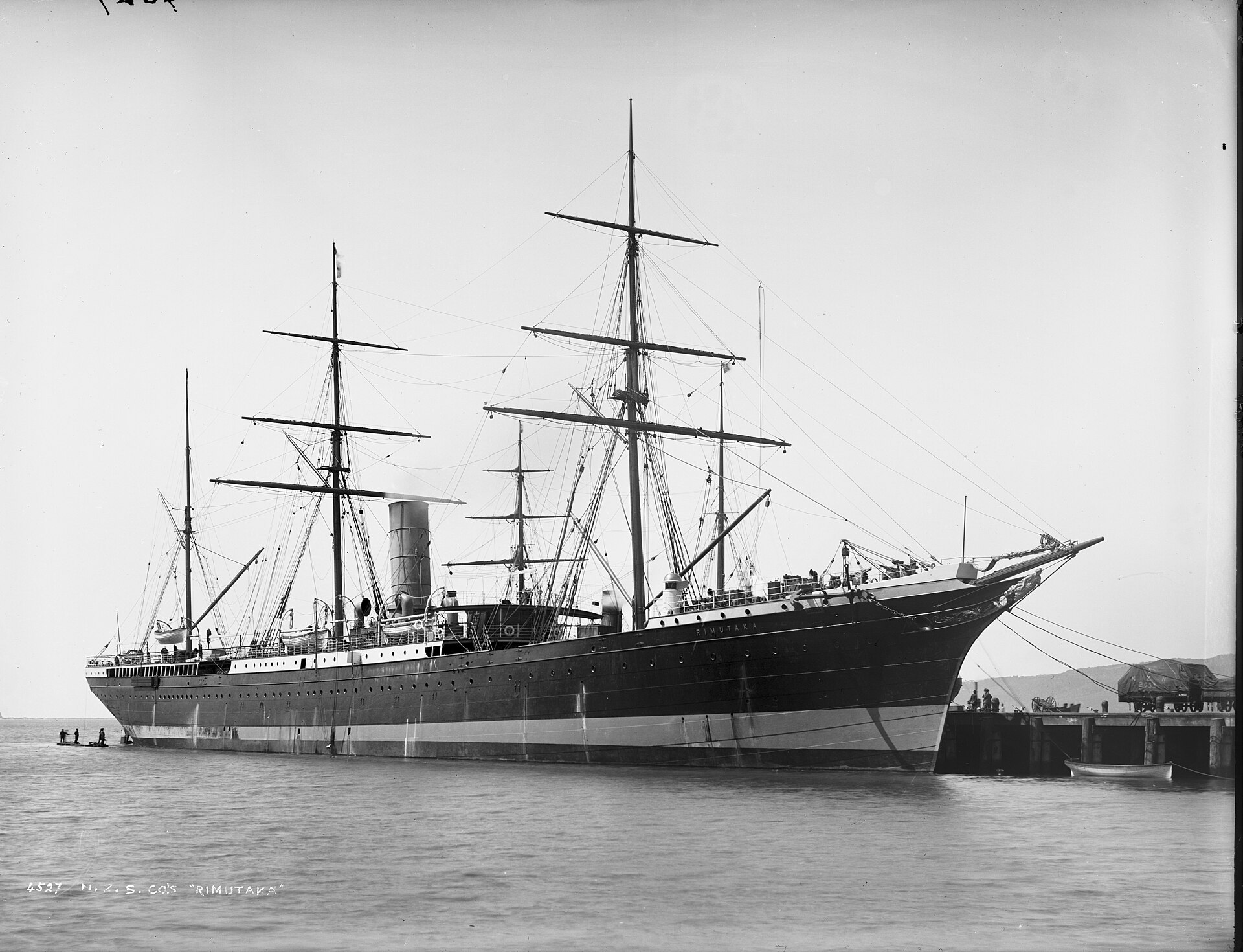 A 1880s glass plate photograph of the sailing ship Rimutaka tied up at a busy wharf, with the photography studio's handwritten catalogue number 4527 visible on the plate itself