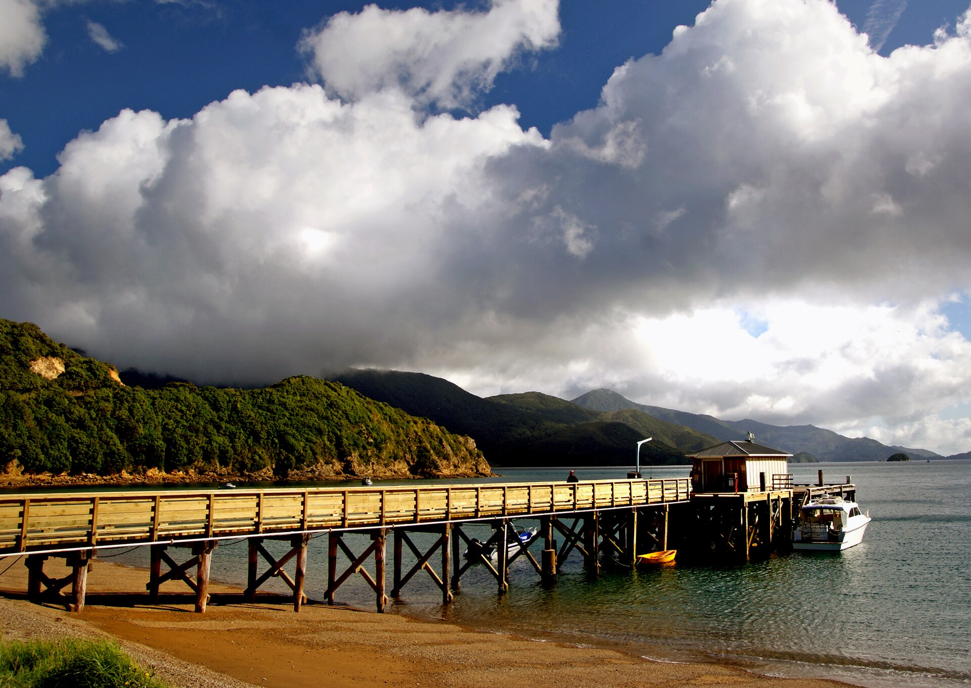 A long wooden jetty reaching into calm blue-green water on a clear day